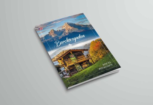 Der Flyer zeigt eine Berglandschaft mit einer Bergspitze im Hintergrund, einen Holzhaus im Vordergrund, grüne Wiese und bunte Bäume, mit dem Titel "Berchtesgaden" und dem Untertitel "and its Attractions".