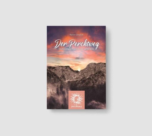 Buchcover mit Berglandschaft bei Sonnenuntergang, Himmel in Orange- und Violetttönen, der Titel "Der Perchtweg" in geschwungener Schrift, Untertitel "Ein Pilgerweg rund um den Untersberg", sowie ein Logo mit einer Sonne und einem Gesicht am unteren Rand.