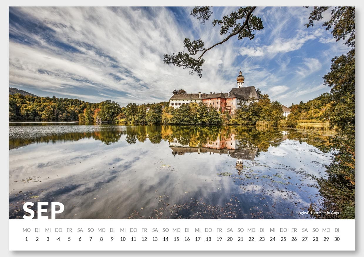 Kalenderbild für den Monat September mit einer Landschaftsansicht eines Sees, auf dem die Spiegelung eines Schlosses, Bäume und ein bewölkter Himmel sichtbar sind, in der unteren linken Ecke die großen weißen Buchstaben 'SEP' für September.
