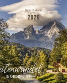 Berglandschaft mit hohen Bergen im Hintergrund, bewaldeten Hügeln und einem Haus am Fluss im Vordergrund, unter einem bewölkten Himmel, mit Text über die Landschaft, der den Namen "Zeitenwandel in Berchtesgaden 2026" und den Namen "Marika Hildebrandt" zeigt.